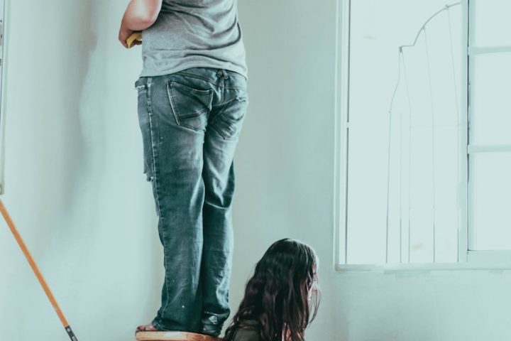 woman in gray t-shirt and blue denim jeans sitting on brown wooden seat