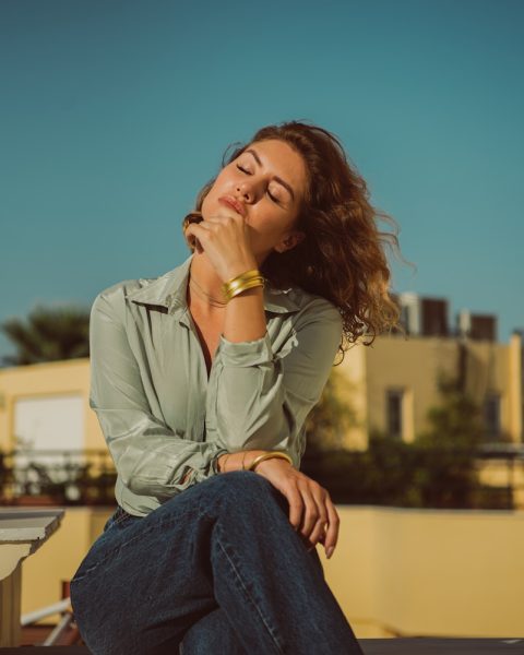 a woman sitting on a ledge with her eyes closed