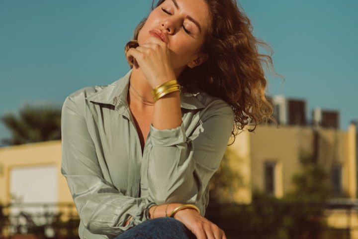 a woman sitting on a ledge with her eyes closed