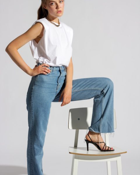 woman in white tank top and blue denim jeans sitting on white chair