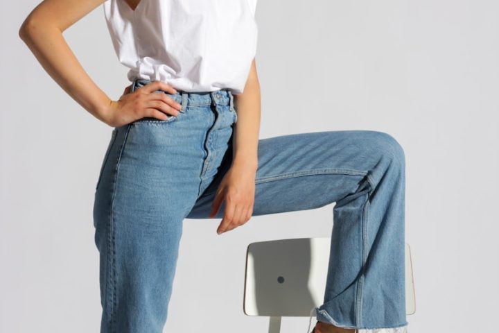 woman in white tank top and blue denim jeans sitting on white chair