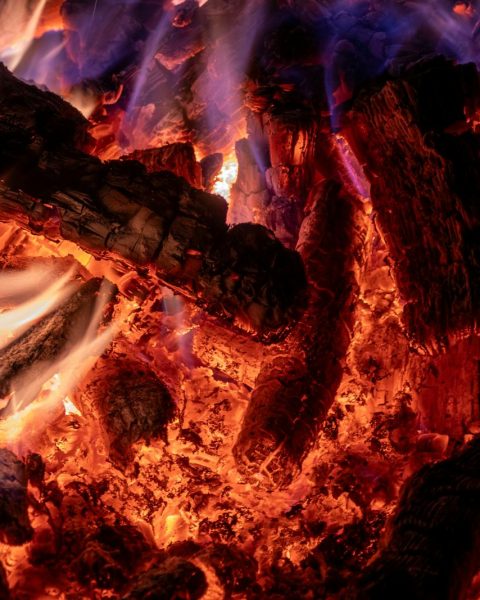 A detailed view of glowing embers and flames from burning wood, showcasing intense heat.
