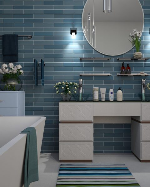 Elektrische handdoekradiator gemonteerd op een witte badkamermuur naast een douche