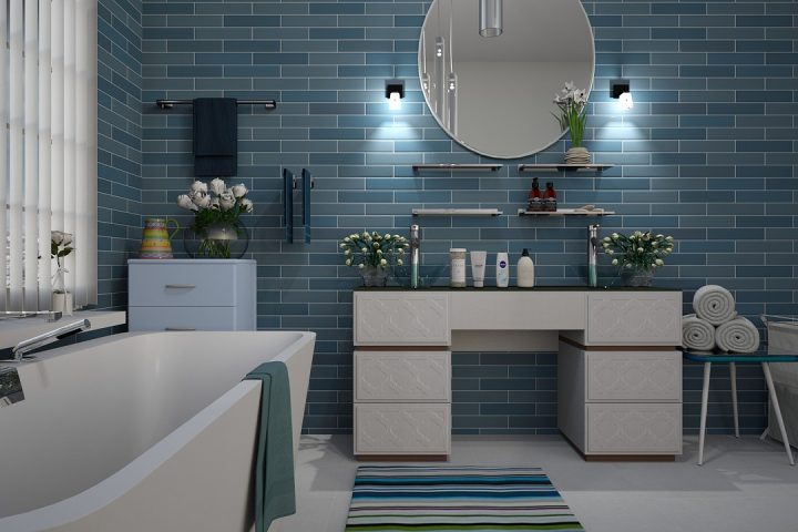 Elektrische handdoekradiator gemonteerd op een witte badkamermuur naast een douche