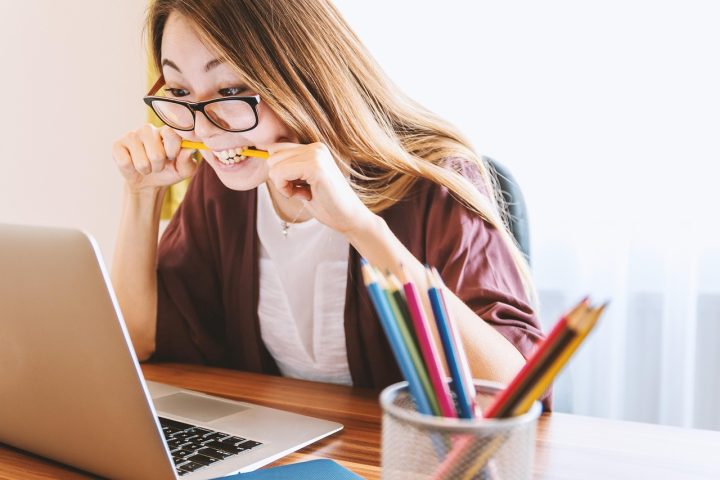 Persoon met bril die werkt achter een computerscherm op kantoor