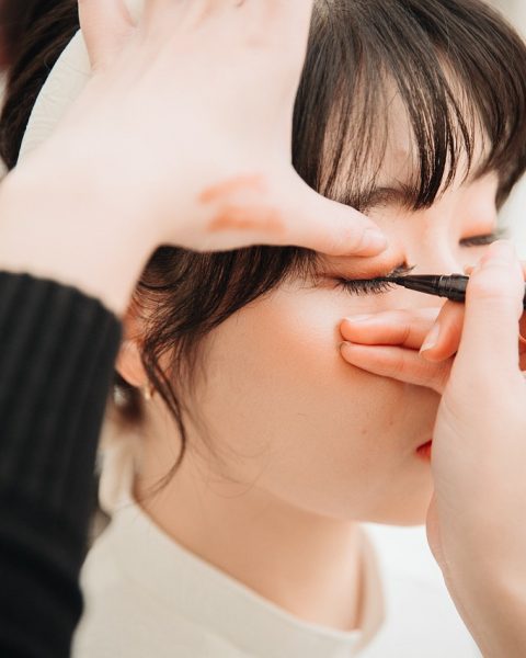 Vrouw brengt eyeliner aan voor een spiegel op een toilettafel