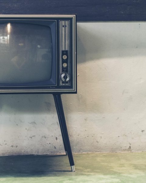 Een retro televisiestudio met een presentator achter een bureau, symbool voor de nostalgische wereld van de Vlaamse televisie