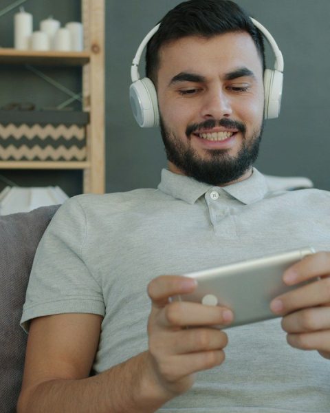 Man wearing headphones plays game on smartphone