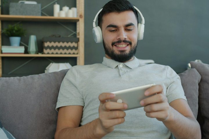 Man wearing headphones plays game on smartphone