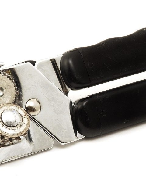 Een handige blikopener op een keukentafel naast een blik groenten