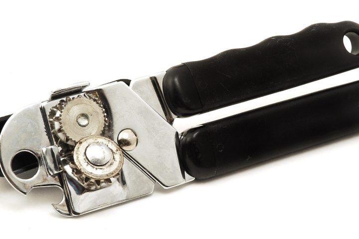 Een handige blikopener op een keukentafel naast een blik groenten