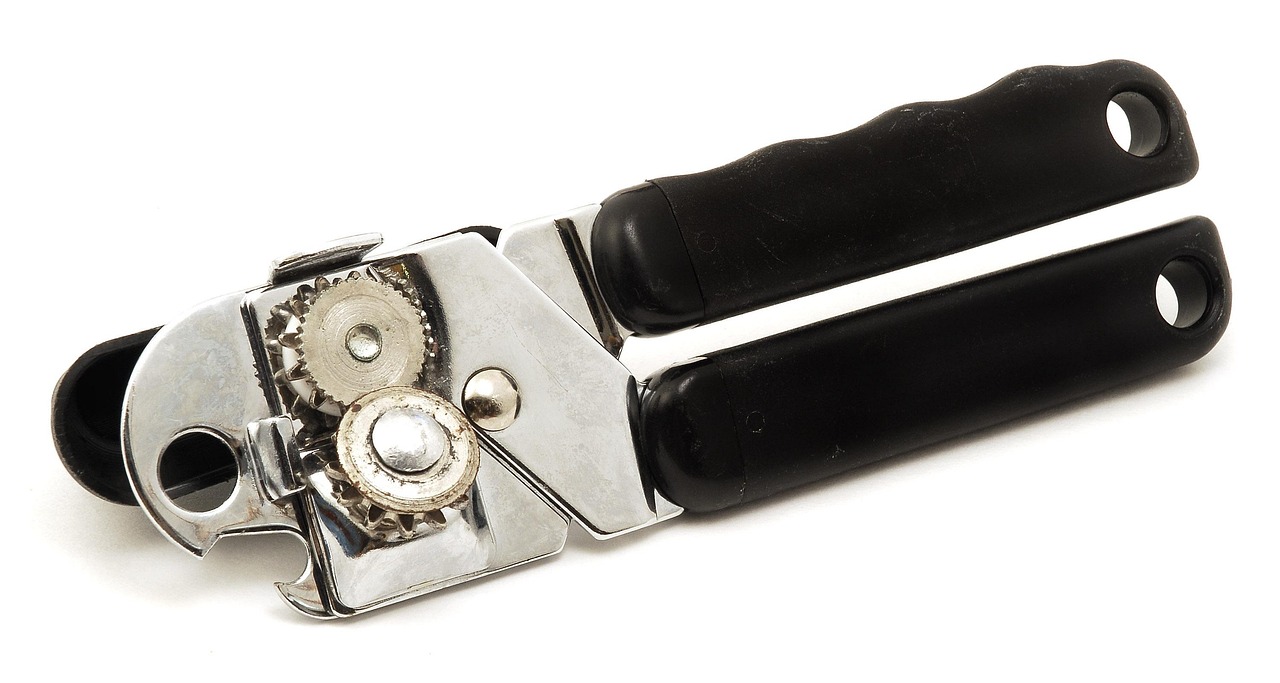 Een handige blikopener op een keukentafel naast een blik groenten