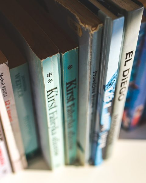Oude vergeelde boeken op een houten boekenplank, met zichtbare kleurverschillen tussen de bladzijden