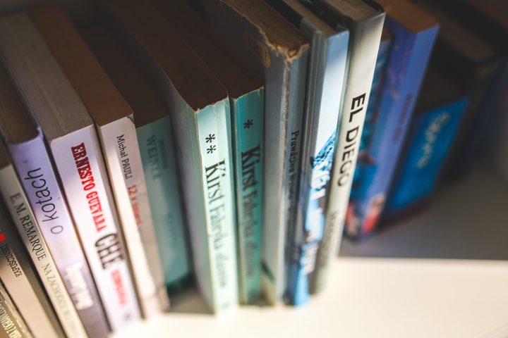 Oude vergeelde boeken op een houten boekenplank, met zichtbare kleurverschillen tussen de bladzijden